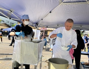 写真：中学生と調理師が屋外で一緒に料理をしている様子